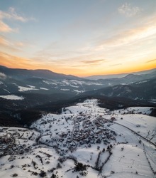 Beautiful aerial landscape with a small village nestled among the snowy mountain slopes of the Rhodopes, Bulgaria in the winter morning