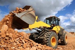 Front end loader dumping stone and sand in a mining quarry