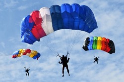 Three colorful parachutes on blue sky.