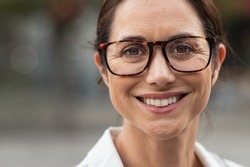 Portrait of mature businesswoman wearing eyeglasses and looking at camera. Close up face of cheerful woman with spectacles smiling outdoor. Confident beautiful entrepreneur wearing specs.