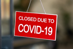 Temporarily closed sign for Covid-19 in small business activity. Information notice sign about quarantine measures. Close up on a red closed placard in the window of a shop for coronavirus.