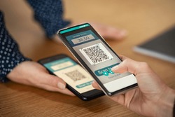 Close up of client hand holding phone and scanning qr code to transfer money. Girl hands holding smartphone to scan code for digital payment. Screen scanning with smartphone for qr-code payment.