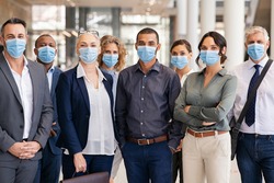 Portrait of successful group of business team wearing surgical mask for safety against coronavirus. satisfied businessmen and businesswomen standing together with face masks and looking at camera.