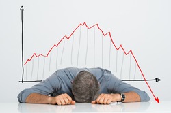 Depressed Businessman Leaning His Head Below a Bad Stock Market Chart