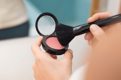 Close up of woman hands with makeup brush holding pink blush. Female hands holding blush box and black brush for make up. Hand of young woman using cosmetic at morning.