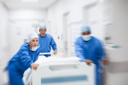 Nurse and doctor in a hurry taking patient to operation theatre. Patient on hospital bed pushed from surgeon to emergency theatre. Team of doctors and surgeon rushing patient.