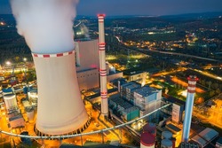 Ledvice, Czech Republic - November 5 2021: Ledvice power plant owned by CEZ. Aerial view of chimneys, cooling tower and buildings in the evening. Industrial lights from above.