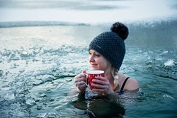 Ice hole swimming, Girl with christmas cup of hot tea in a frozen lake, winter challenge.