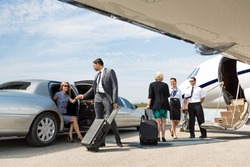 Business partners about to board private jet while airhostess and pilot greeting them