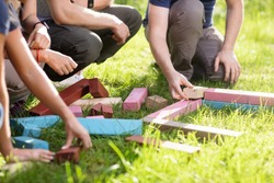 Cropped Image Of Friends Playing With Building Blocks On Field