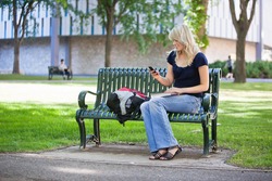 Young female student using cell phone while sitting in college campus