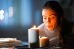 Beautiful woman blowing out candles in the living room at home in the night