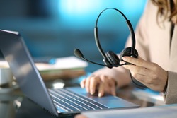 Close up of a tele marketer holding headset using laptop at homeoffice