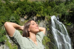 Happy woman breathing fresh air and resting in a waterfall in the mountain