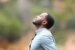 Side view portrait of a man with black skin breaths fresh air outside