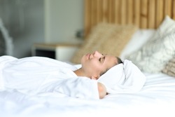 Happy woman resting lying on the bed after showering at home