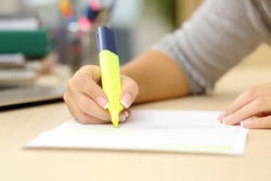 Close up of a student hand underlining a document on a desk at home