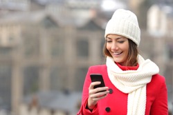 Girl texting in a mobile phone warmly clothed in the street in winter