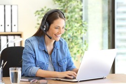 Freelance operator working in telemarketing on line with headsets and a laptop in a desktop at office
