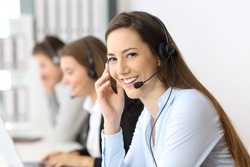 Happy telemarketer looking at you at office with other workers in the background