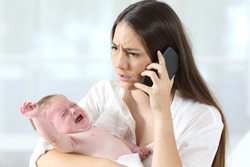 Mother calling to a doctor on phone worried about her baby crying desperately at home