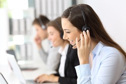Happy telemarketer working at call center with other employees in the background