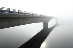 Concrete bridge over the sea in the middle of a deep fog