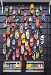 Many multicolored vintage Dutch Klomp shoes on black wood panel background