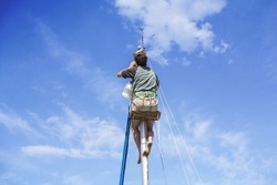 Young man hanging and repairs yacht mast