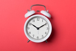 White vintage alarm clock on red background. Time concept