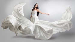 beautiful young girl in flying white dress. Flowing fabric. Light white cloth flying in the wind