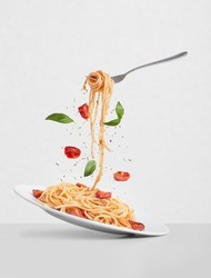 pasta with tomatoes and basil on a gray background