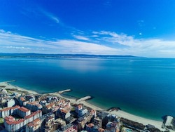 Panoramic bird's eye view over small ancient resort town of Pomorie with old European small houses and quiet calm empty streets, washed by the sea spring turquoise Black Sea on clear day in Bulgaria