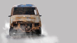 Burnt out delivery van isolated on grey background