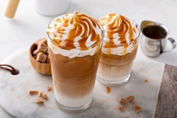 Iced caramel latte topped with whipped cream and caramel sauce, refreshing and sweet coffee drink