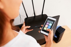 Hands of woman connecting smart home application on her phone to wi-fi router