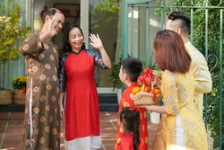 Happy grandparents greeting their children and grandchildren who came for Lunar New Year celebration at house entrance