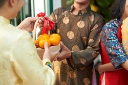 Man giving basket of ripe mandarins to his senior dad when he is visiting for Lunar New Year celebration