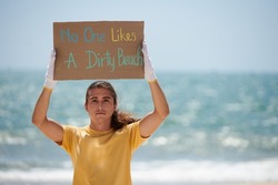 Young man showing no one likes dirty beach placard her made for protest