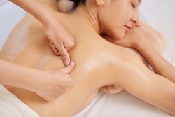 Masseur giving deep tissue back massage to young female client