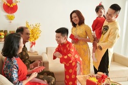 Smiling preteen boy greeting grandparents with bow when family visiting them fot Tet celebration