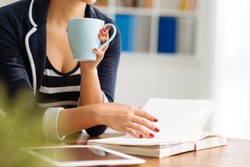 Cropped image of woman drinking coffee and reading a book