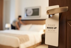 Maid cleaning the room with please make up my room sign on the door