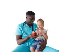 children's African-American doctor tells a little girl about proper nutrition holding an apple in her hands