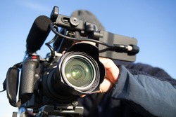 man filming with 4k camcorder against the background of blue sky