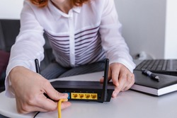 Redhead Woman connects the internet cable to the router's socket. Fast and wireless internet concept