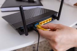 woman connects the internet cable to the router's socket. Fast and wireless internet concept