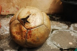 Old deflated soccer ball. Broken football. Brown ball with big ripped