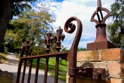 Ornate and weathered wrought iron fence affixed to orange yellow gate posts