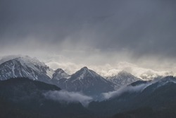 Mountains covered in snow with dark cloudy sky in rainy day